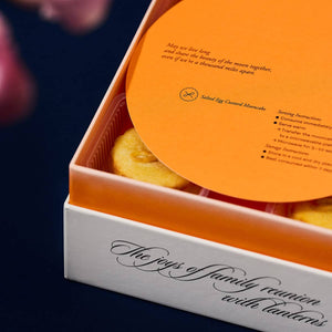 A 2022 mooncake gift set in gradient orange with salted egg custard mooncakes inside and an orange info card on top of it