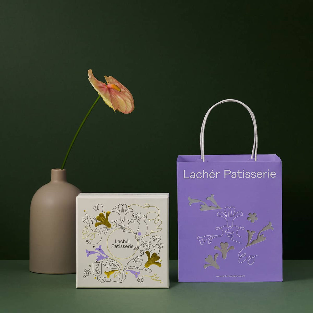 The front of a 2022 mooncake gift set on a table with a paper bag lantern and a vase of flower beside it.