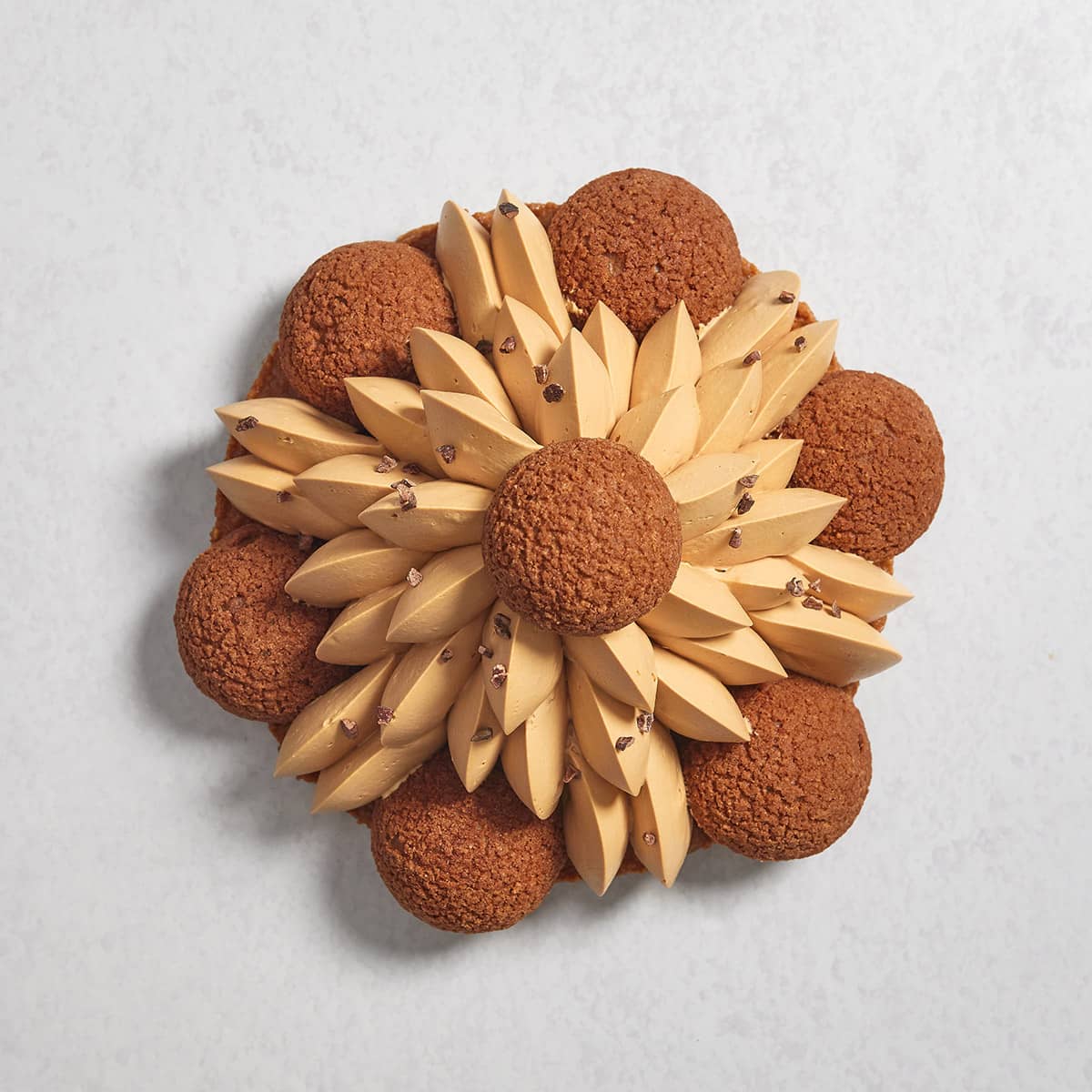 The top view of a Salted Caramel Saint-Honore cake with 6 choux puffs and a pyramid-like salted caramel piping topped with another choux puff.